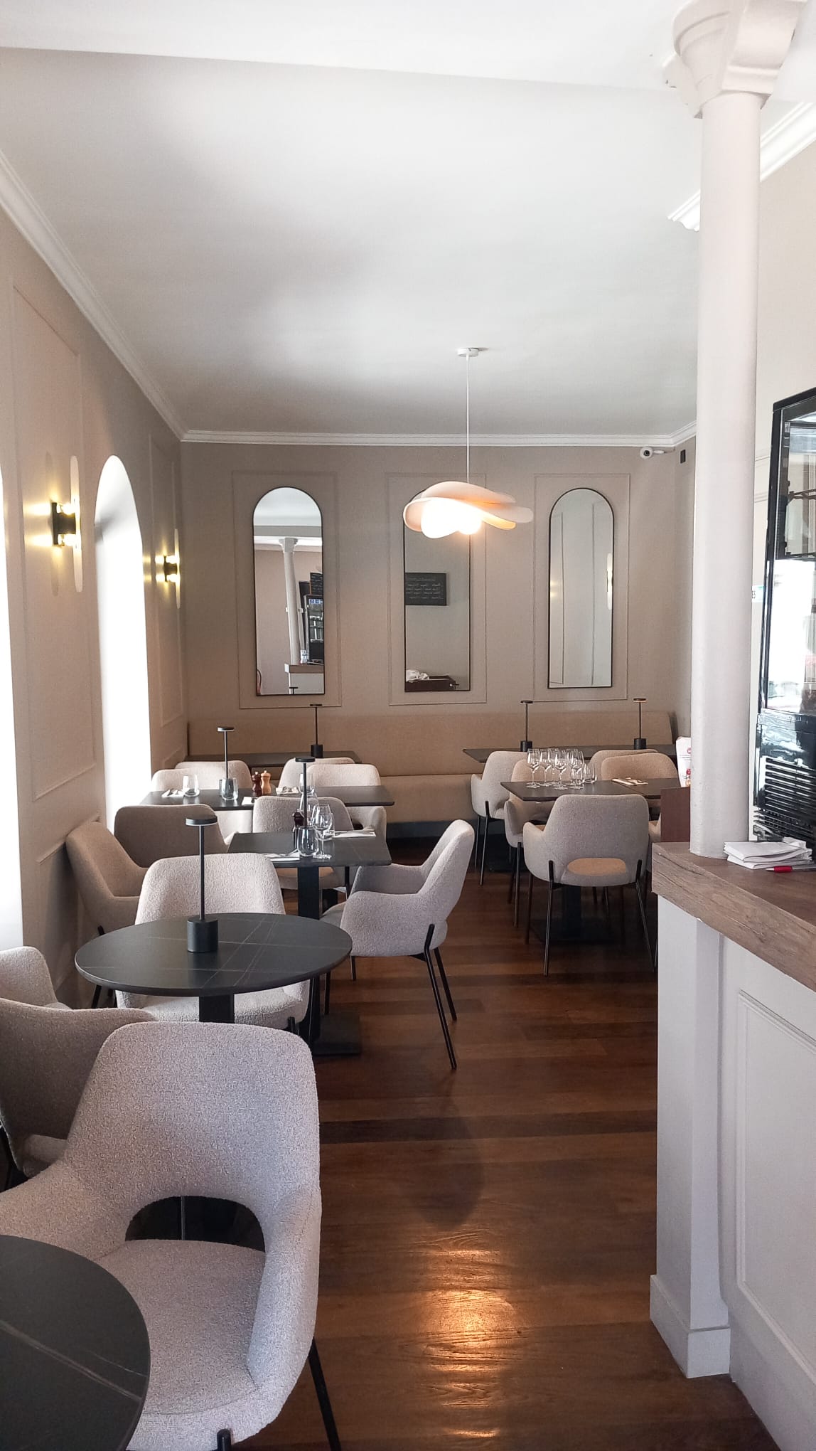 Salle de la brasserie, tables dressées et fauteuils bouclette